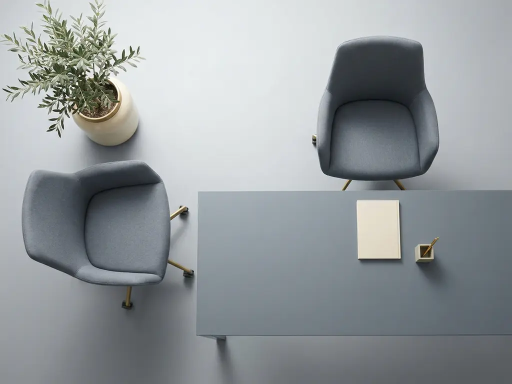 Twee elegante bureaustoelen op een minimalistisch bureau, één stoel gedraaid naar een potplant, in leisteen en ivoor tinten met gouden accent.