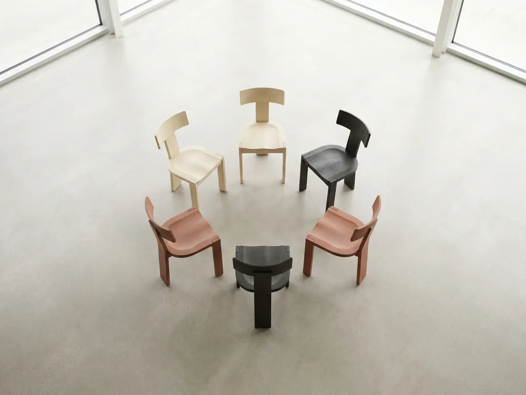 Vijf houten stoelen in een cirkel op betonnen vloer, bovenaanzicht, natuurlijk licht, warme tinten.